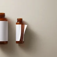Label failure on the small amber bottle, its blank white label lifting at one edge while the same label stays flat on the larger bottle