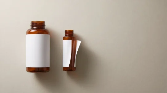 Label failure on the small amber bottle, its blank white label lifting at one edge while the same label stays flat on the larger bottle